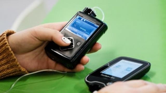 Hand holding a glucose monitor on a table