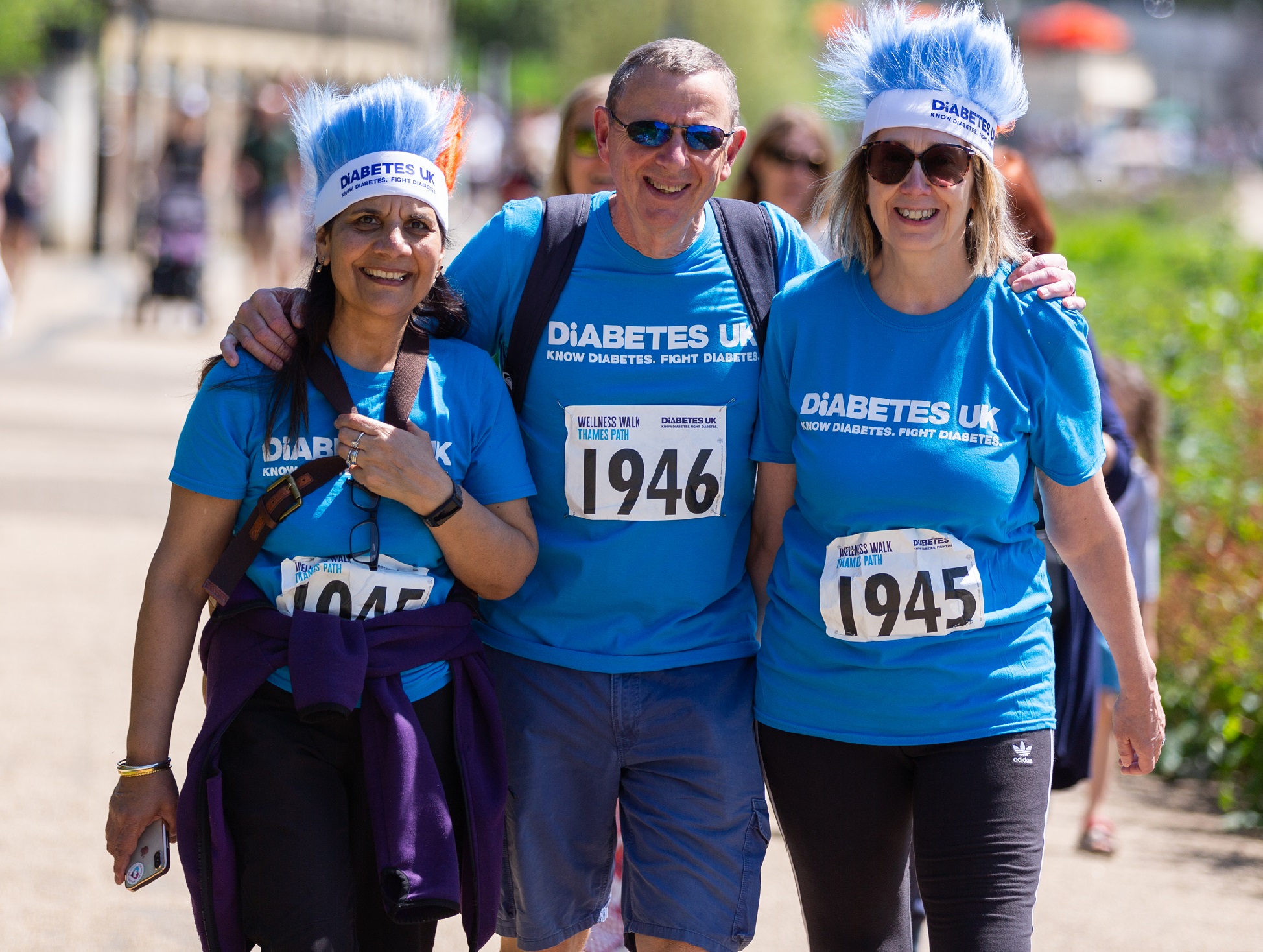 Three people walking together smiling at camera