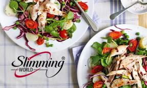 Two plates of watercress and new potato salad topped with mackerel on a blue and white striped table cloth.