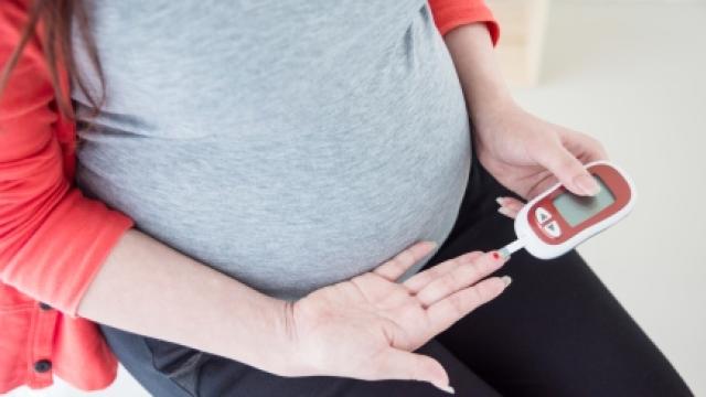 A pregnant women doing a finger prick test using a blood test kit