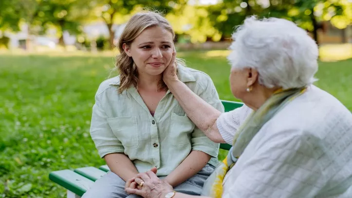 young woman old woman in park sad