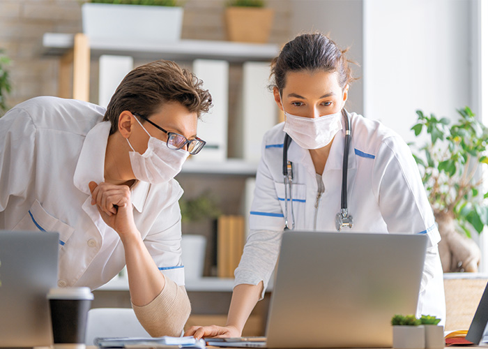 two doctors in front of a laptop