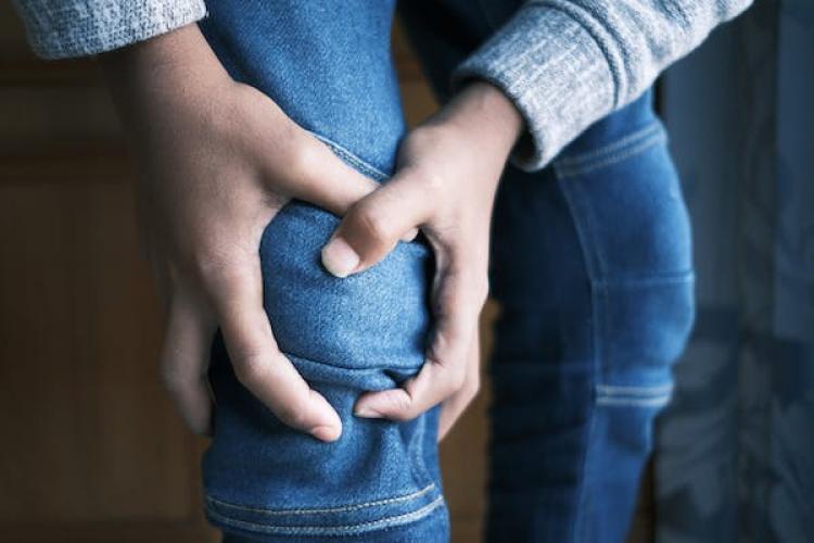 Close-up of person holding their knee in pain