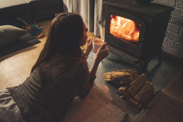 Woman lies down in front of a fireplace